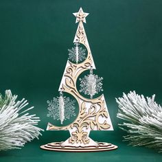 a paper cut christmas tree with snowflakes around it on a green tablecloth