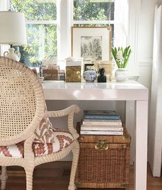 a wicker chair sitting in front of a white desk with a lamp on it