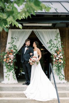 a bride and groom standing in front of an open doorway with floral decorations on it