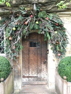 an old door is decorated with greenery and fruit