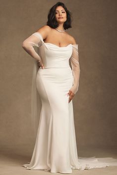 a woman in a white wedding dress posing for a photo with her hands on her hips