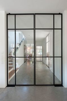 an empty room with glass doors and stairs leading to the second floor in front of it