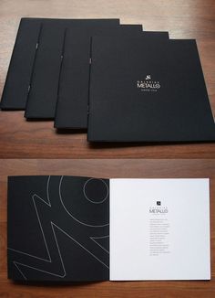 four black folders sitting next to each other on top of a wooden table with white paper