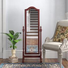 a white chair sitting next to a tall wooden mirror on top of a hard wood floor