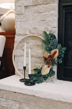 a wreath and two candles sitting on top of a mantle