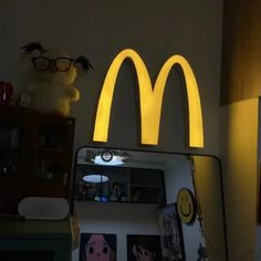 a lighted mcdonald's sign above a mirror in a room with pictures on the wall