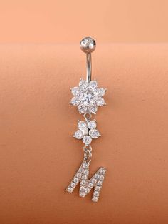 the letter m is attached to a navel bar with clear crystal flowers on it