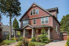 a red house with lots of windows on the front and side of it, surrounded by greenery