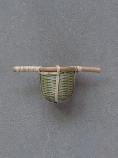 a small basket with a wooden handle on the ground