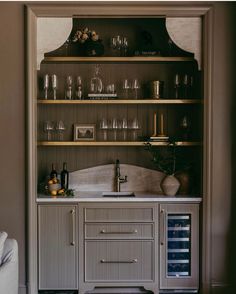 an open cabinet with wine glasses and bottles on it