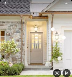 the front door of a house with two lights on it and flowers in pots outside