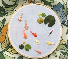 a close up of a cross stitch pattern with fish and waterlilies on it