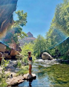 a woman standing on rocks in the middle of a river