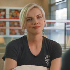 a woman sitting at a table with food in front of her and looking off into the distance