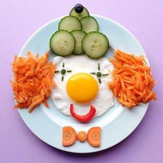 a plate with carrots, cucumbers and an egg in the shape of a face