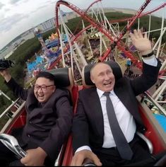 two men in suits and ties are riding on a roller coaster at an amusement park