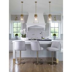 three lights hanging over a kitchen island with stools and counter top in front of it