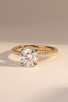 a yellow gold engagement ring with a round diamond in the center and two rows of diamonds around it