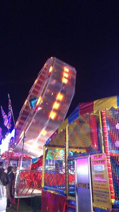 people are walking around an amusement park at night