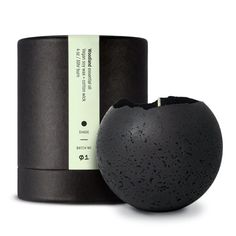 a black vase sitting on top of a table next to a container with a label