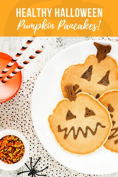 three pumpkin pancakes on a white plate with sprinkles and candy in the background