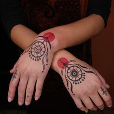 two women with matching tattoos on their arms and hands, both holding each other's hand