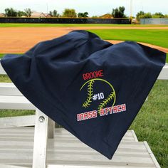 a baseball towel sitting on top of a white bench in front of a green field