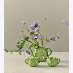 a green vase with purple flowers in it