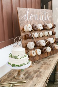 a table topped with a cake and donuts next to a sign that says donuts