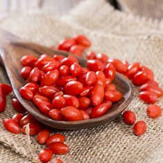 a wooden spoon filled with red tomatoes on top of a table