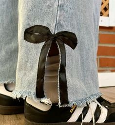 a pair of black and white adidas shoes with a ribbon tied around the ankles