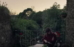 a woman is sitting at an outdoor table with a book in her hand and reading