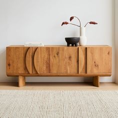 a wooden sideboard with two vases on it and a rug in front of it