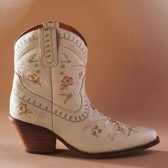 a pair of white cowboy boots with embroidered flowers