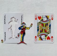 two playing cards, one with the joker and the other with the queen of hearts