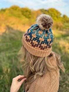 a woman wearing a knitted hat with a pom - pom on top