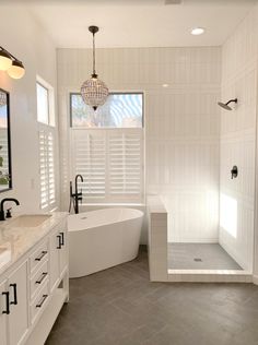 a large bathroom with white fixtures and gray tile flooring, along with a walk in shower