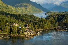 an island in the middle of a lake surrounded by trees and mountains with houses on it