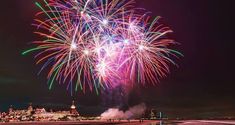 fireworks are lit up in the night sky over a cityscape and beach area