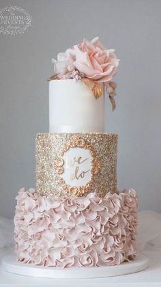 a three tiered cake with pink and gold ruffles on the bottom layer