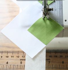 the sewing machine is next to some paper and measuring tape on a table with rulers