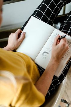 a person sitting down writing on a notebook