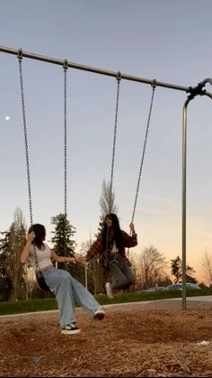 two women sitting on swings in a park