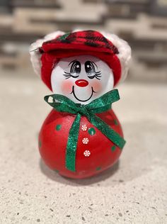 a red and green christmas ornament with a snowman on it's head