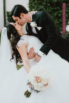 a bride and groom kissing in front of a building