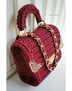 a crocheted handbag hanging on the side of a door with chain around it