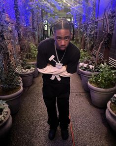 a man standing in a greenhouse holding onto a pair of shoes