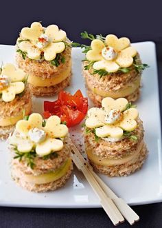 small sandwiches are arranged on a plate with tomatoes and other toppings, including cheese