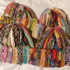 several multicolored knitted hats laying on top of each other