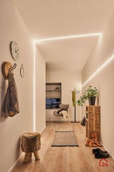 a long hallway with wooden floors and lights on the walls, along with plants in pots